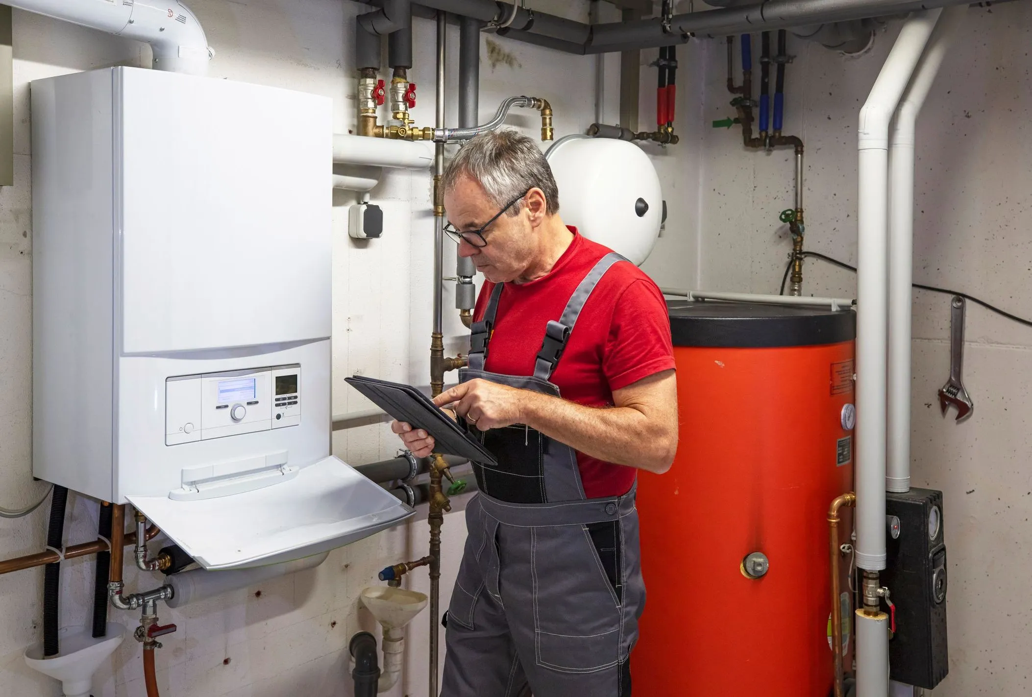 SHK Handwerker arbeitet mit Software auf dem Tablet an einer Heizung