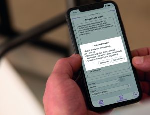Monteur hält Smartphone mit der Labelwin Mobile App; ein KI-Dialog übersetzt einen polnischen Freitext zur ausgeführten Arbeit und schlägt eine strukturierte deutsche Zusammenfassung zur Übernahme vor.
